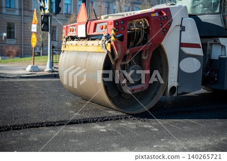 Heavy road roller machine slowly moving over freshly laid asphalt substance and smoothing surface. 140265721
