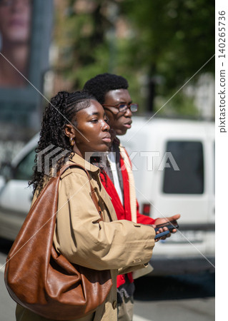 Fashionable focused married couple african american man and woman stand on street waiting for taxi. Fashionable focused married couple african american man and woman stand on street waiting for taxi. 140265736