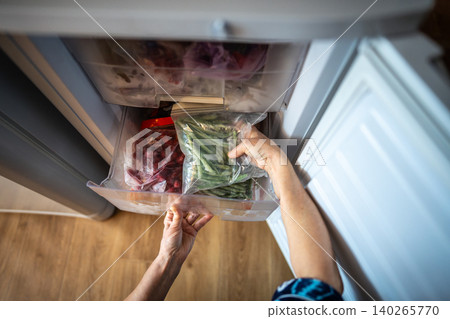 Hands with green beans from freezer in zip bag. Winter storage, fresh healthy homemade meal cooking Hands with green beans from freezer in zip bag. Winter storage, fresh healthy homemade meal cooking 140265770