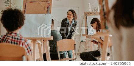 Happy Hispanic adult female teacher instructing teen students in bright art classroom 140265965