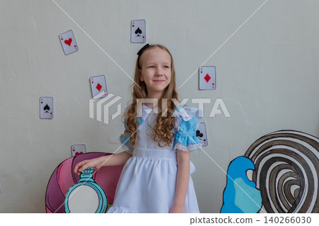 Gentle White Girl In Alice Costume Leaning On Pastel Prop, Calm Studio Portrait With Playing Cards And Whimsical Backdrop, Soft Smile, Longhair Curls And Serene Mood For Family Or Editorial Use Gentle White Girl In Alice Costume Leaning On Pastel Prop, Calm Studio Portrait With Playing Cards And Whimsical Backdrop, Soft Smile, Longhair Curls And Serene Mood For Family Or Editorial Use 140266030