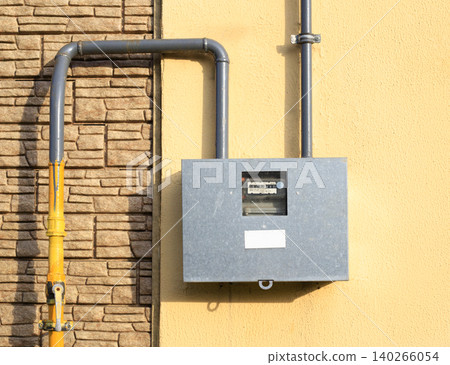 Outdoor gas meter box with pipelines on house wall, residential energy utility supply measurement device closeup Outdoor gas meter box with pipelines on house wall, residential energy utility supply measurement device closeup 140266054