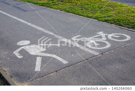 Angle view of white road marking icons on asphalt lane, pedestrian and bicycle route division for urban traffic safety Angle view of white road marking icons on asphalt lane, pedestrian and bicycle route division for urban traffic safety 140266060