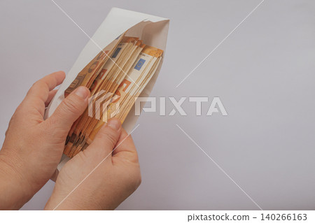 Female hands holding a white envelope with 50 Euro banknotes and pulling out one bill. Clean minimalist composition on a light background with a large copy space Female hands holding a white envelope with 50 Euro banknotes and pulling out one bill. Clean minimalist composition on a light background with a large copy space 140266163