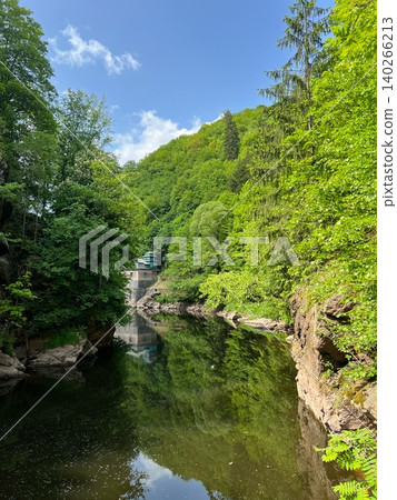 Scenic river surrounded by lush green trees and rocky cliffs in nature Scenic river surrounded by lush green trees and rocky cliffs in nature 140266213