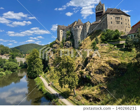 Historic castle on hillside overlooking river and lush green landscape 140266231
