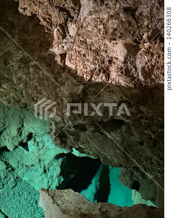 Natural cave formation with turquoise water pool and rocky textures Natural cave formation with turquoise water pool and rocky textures 140266308