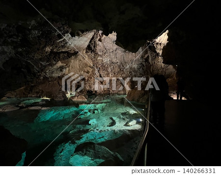Underground cave with illuminated water and rock formations in darkness Underground cave with illuminated water and rock formations in darkness 140266331