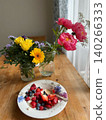 Fresh fruit salad with mixed berries and flowers on wooden table 140266333