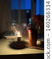 Candlelight on table with incense holder and decorative flowers in background 140266334