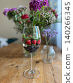 Glass of mixed berries and mint on wooden table with floral arrangement 140266345