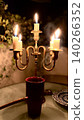 Candlelit brass candelabra with four candles on glass table setting 140266352