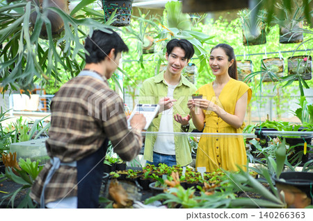 Nursery plant owner calculating plant price Nursery plant owner calculating plant price 140266363