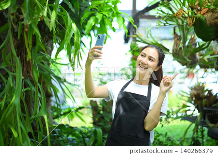 Smiling woman taking selfie in greenhouse, blending lifestyle, social media, and nature Smiling woman taking selfie in greenhouse, blending lifestyle, social media, and nature 140266379