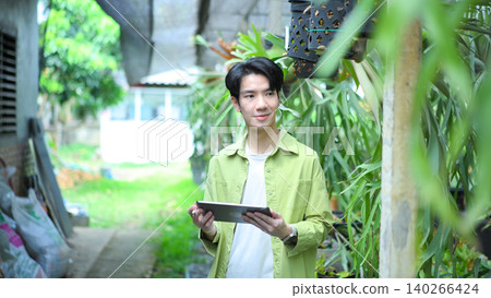 Gardener using tablet to check staghorn fern in greenhouse Gardener using tablet to check staghorn fern in greenhouse 140266424