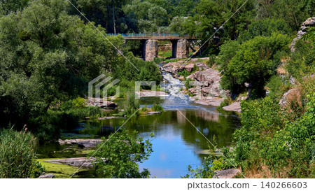 Bridge and summer river flowing among green rock hills Bridge and summer river flowing among green rock hills 140266603