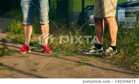 Two people.Men meet outdoor.Leisurely conversation.Shorts and sneakers. Two people.Men meet outdoor.Leisurely conversation.Shorts and sneakers. 140266673