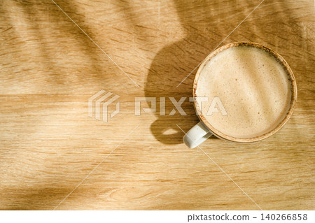 Top view of coffee cup on wooden desk with copy space and natural sunlight Top view of coffee cup on wooden desk with copy space and natural sunlight 140266858