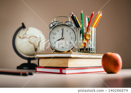 Global education workspace with textbooks and alarm clock, knowledge development concept 140266874