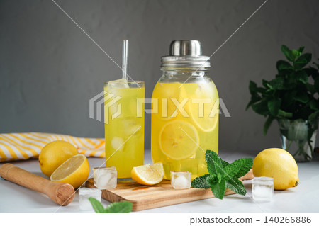Homemade lemonade with mint and ice served in glass and jar, summer beverage advertising concept Homemade lemonade with mint and ice served in glass and jar, summer beverage advertising concept 140266886