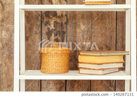 Close up of white bookshelf against grunge wooden wall Close up of white bookshelf against grunge wooden wall 140267131