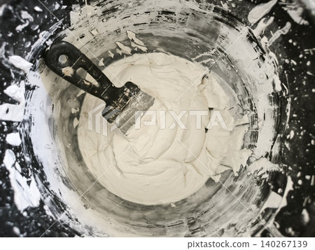 Thick white putty in black paint bucket Thick white putty in black paint bucket 140267139