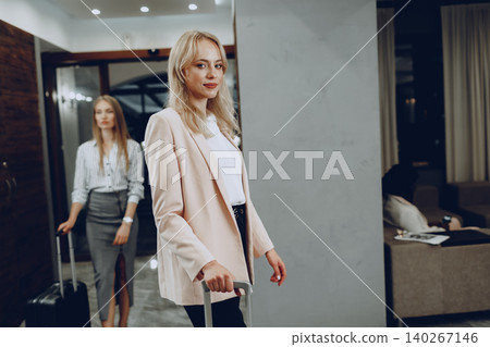 Two young women in formal clothes entering hotel lobby 140267146
