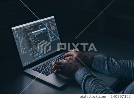 Person working on computer in dark room while coding software at night 140267392