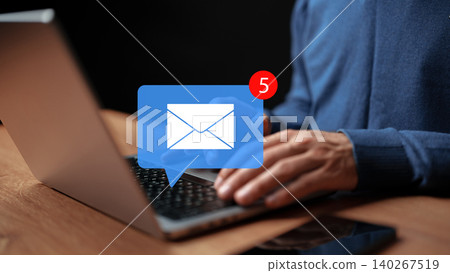 Person checking emails on a laptop while sitting at a wooden table at night Person checking emails on a laptop while sitting at a wooden table at night 140267519