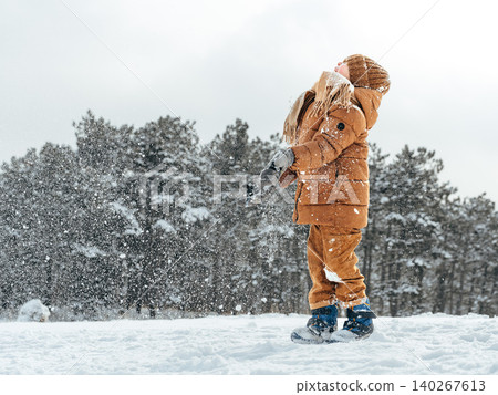 Child plays in snow while wearing warm clothes and enjoying a winter day outdoors Child plays in snow while wearing warm clothes and enjoying a winter day outdoors 140267613