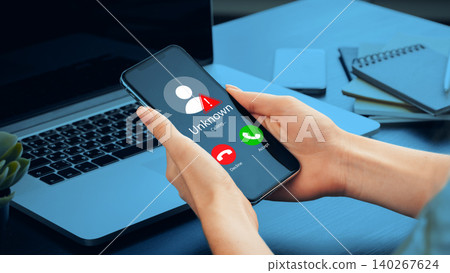 Scam call alert shown on smartphone while working at a desk during the day Scam call alert shown on smartphone while working at a desk during the day 140267624