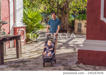 Man walking with baby stroller through Mexican colonial street, colorful architecture, heritage courtyard, fatherhood and family travel with baby concept Man walking with baby stroller through Mexican colonial street, colorful architecture, heritage courtyard, fatherhood and family travel with baby concept 140267648