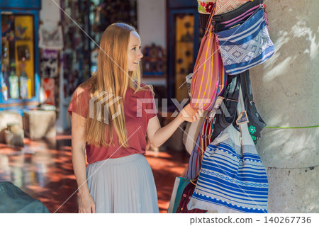 Woman shopping for traditional Mexican textiles and handmade souvenirs in a colorful market, cultural travel, artisan craft and vacation shopping concept Woman shopping for traditional Mexican textiles and handmade souvenirs in a colorful market, cultural travel, artisan craft and vacation shopping concept 140267736