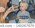 Two year old toddler celebrating birthday while mother cuts cake, family party, childhood milestone, home celebration and sweet moment concept 140267870