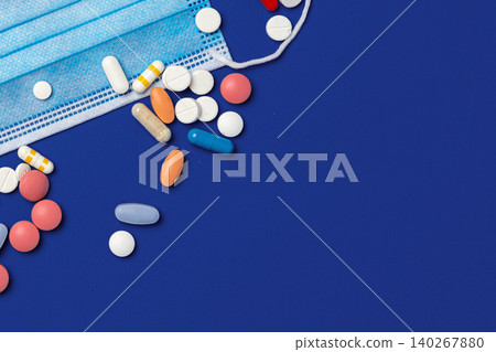 Different types of pills and a medical mask on a blue background Different types of pills and a medical mask on a blue background 140267880