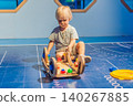 Three year old toddler sitting alone and playing with wooden learning toy at science center, early STEM education, curiosity and child development concept 140267885