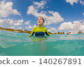 Young boy plays in foamy ocean waves on a sunny beach trip, expressing summer fun, active childhood and vacation concept 140267891