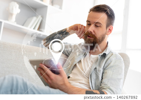 Man checking travel route for taxi on tablet at home during the day Man checking travel route for taxi on tablet at home during the day 140267892