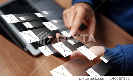 Sending messages through a device with a computer visible in the background Sending messages through a device with a computer visible in the background 140267932