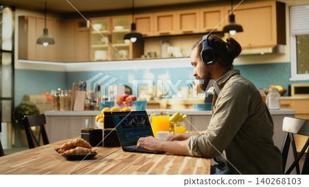 Male video editor and videographer working indoors from home, post production tasks such as timeline editing, color grading and visual effects. Interface shows clips and creative software tools. 140268103