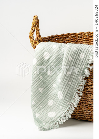 Soft green blanket placed on woven basket for home decor storage in a cozy space Soft green blanket placed on woven basket for home decor storage in a cozy space 140268324