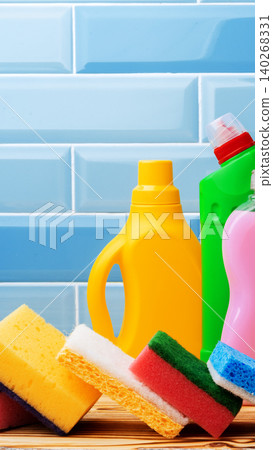 Cleaning supplies and sponges on a wooden surface with blue tiles in the background Cleaning supplies and sponges on a wooden surface with blue tiles in the background 140268331