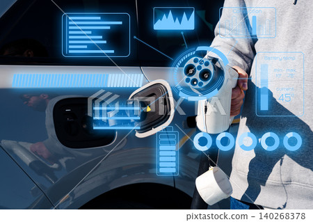 Person holding electric car charger while interacting with display screen in charging station Person holding electric car charger while interacting with display screen in charging station 140268378
