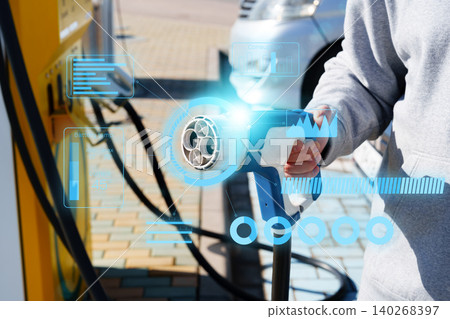 Person holding electric car charger at charging station during day Person holding electric car charger at charging station during day 140268397