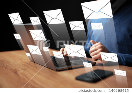 Person typing on a laptop with email notifications displayed on the screen 140268415