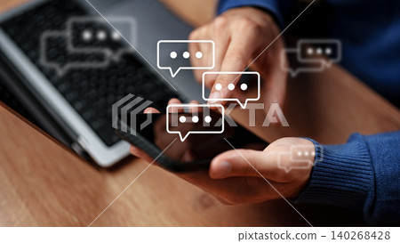 Sending messages on a smartphone while sitting at a desk with a computer nearby Sending messages on a smartphone while sitting at a desk with a computer nearby 140268428
