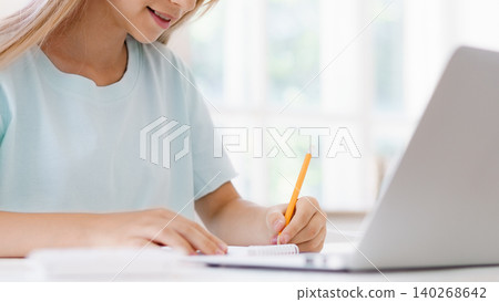 Student writes notes while studying at home during daytime Student writes notes while studying at home during daytime 140268642