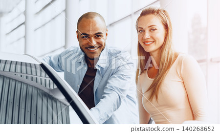 Two people in a car dealership discussing vehicle options during daytime Two people in a car dealership discussing vehicle options during daytime 140268652