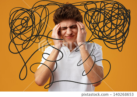 Boy holds head with hands and shows signs of confusion against orange background 140268653