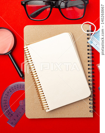 Office supplies on a red table with notebook, glasses, and tools for studying and writing 140268667